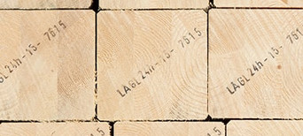 Gestapelte Brettschichtholzbalken mit sichtbarer Jahresringstruktur und Markierungen für den Holzbau.